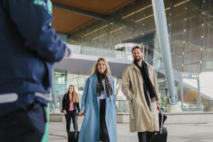 En kvinne og en mann med trillekofferter på vei fra flyplassen til bybanen